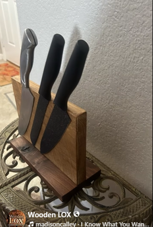 Handcrafted Wooden LOX magnetic knife holder made of walnut and oak wood with three black-handled kitchen knives attached.